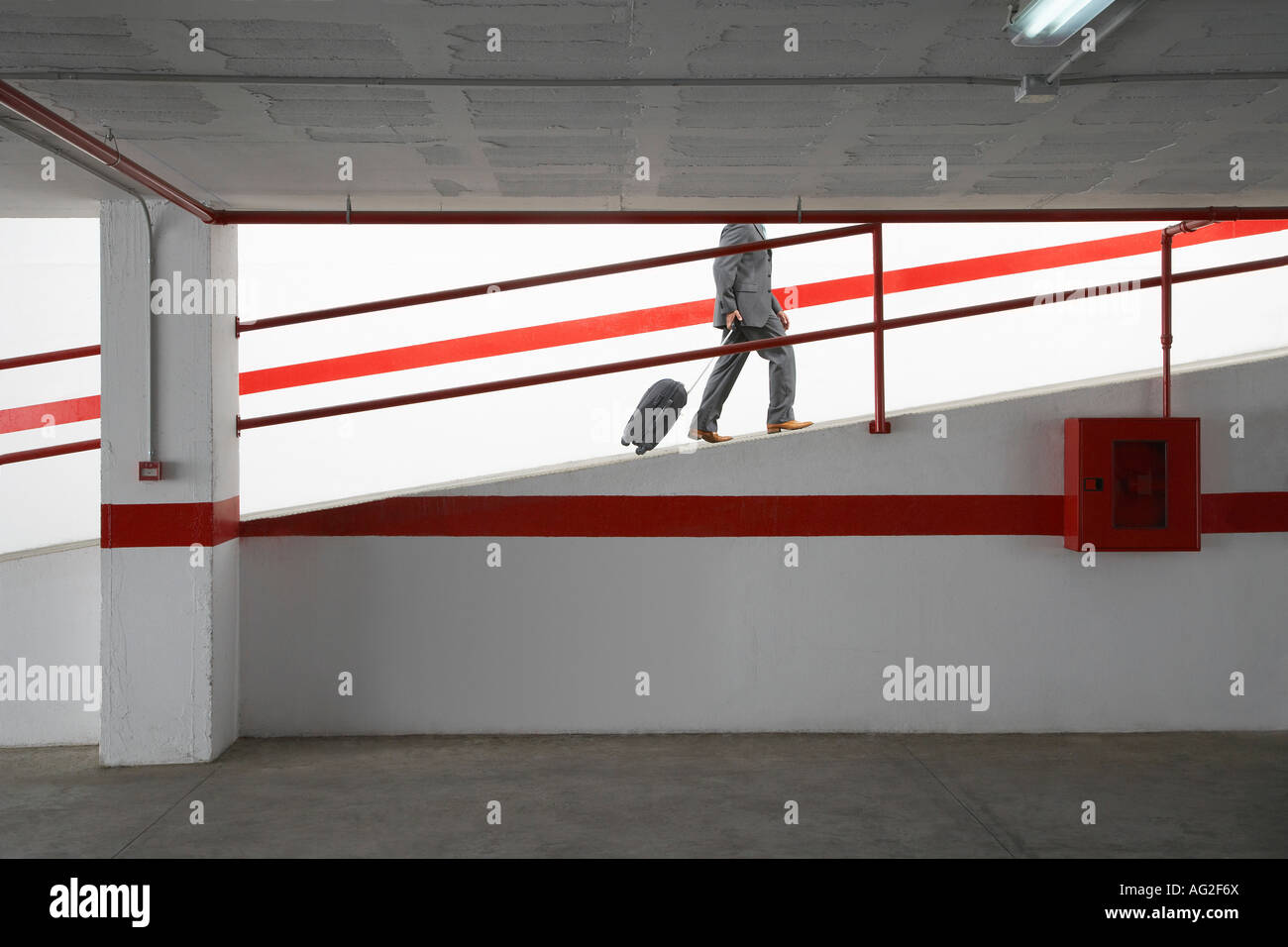 Businessman walking up ramp in parking garage with luggage Stock Photo ...