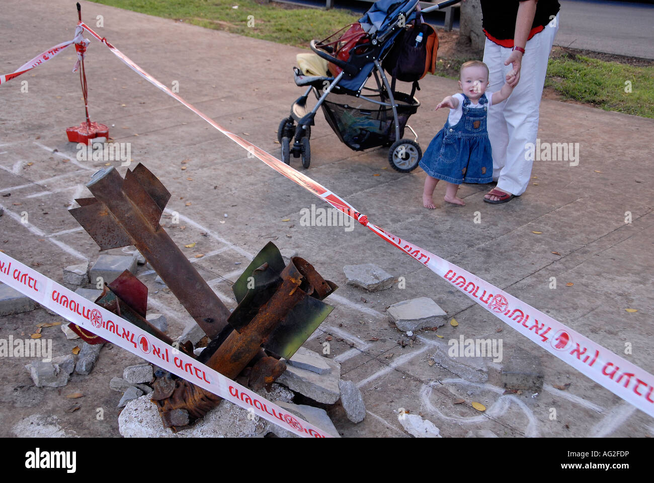 Pedestrians walk past remnants of Qassam rockets that were fired from Gaza Strip to southern Israel displayed in Rothschild avenue, Tel Aviv Israel Stock Photo