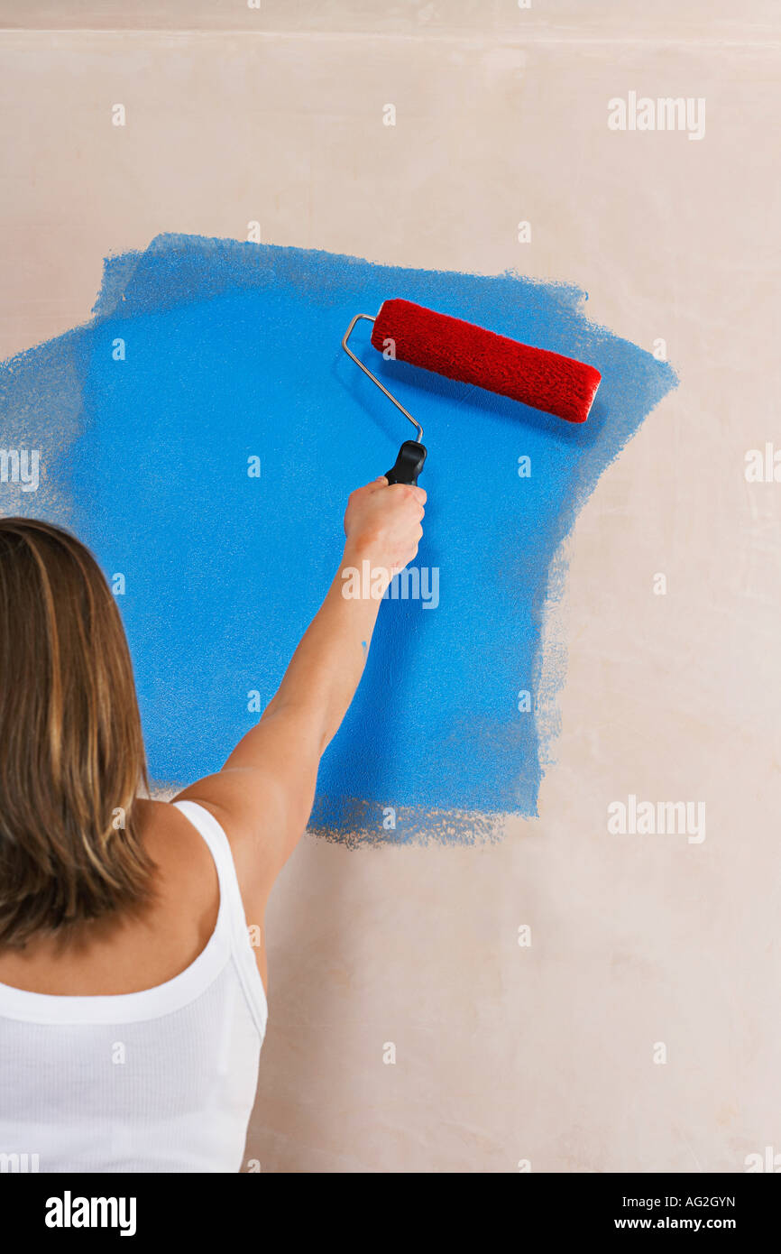 Woman Painting Wall With Paint Roller Back View Stock Photo