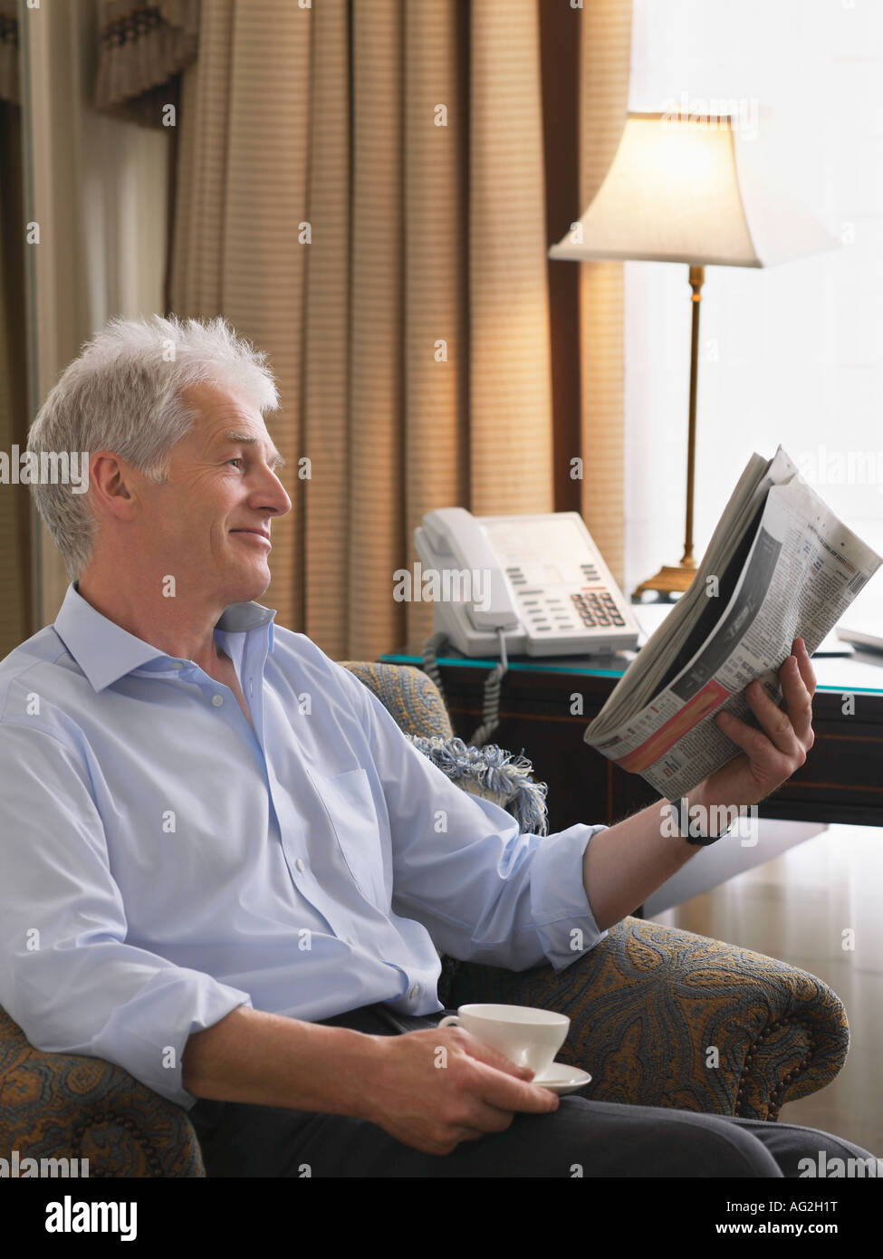 Business man sitting in armchair reading newspaper Stock Photo - Alamy