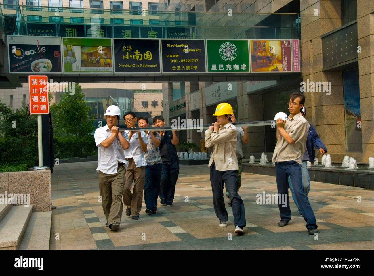 Beijing CHINA, Construction Site Workers Carrying Large Plate Glass Window to Install in Tower of the Regent Hotel Blue collar worker, street posters Stock Photo