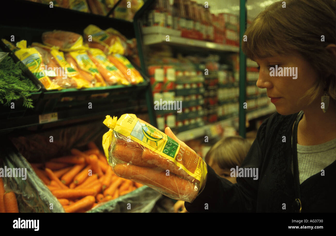 Woman reading label on organic carrots in supermarket shop UK Stock Photo