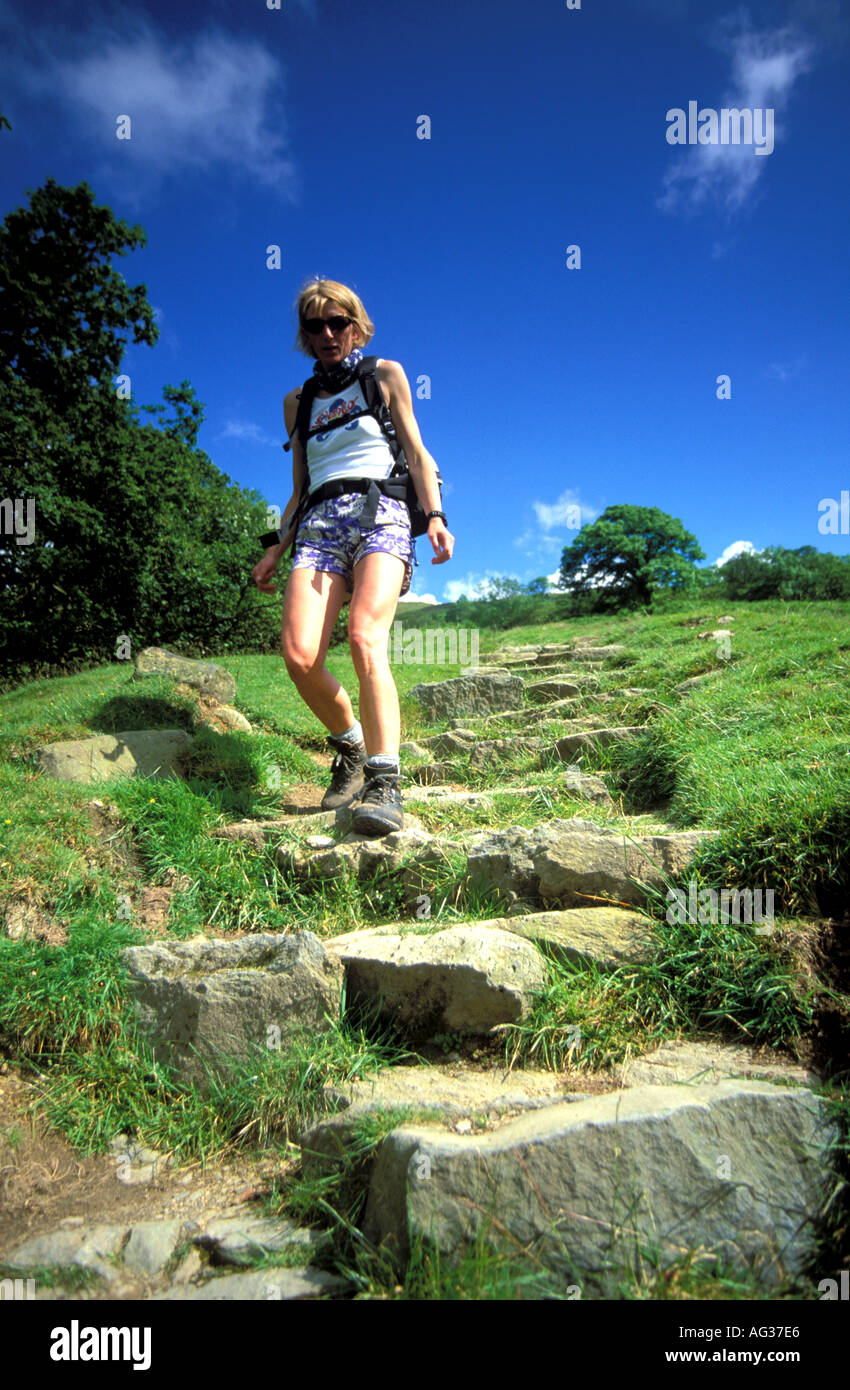 Female walking down some stone steps on a hill on a bright summers day ...