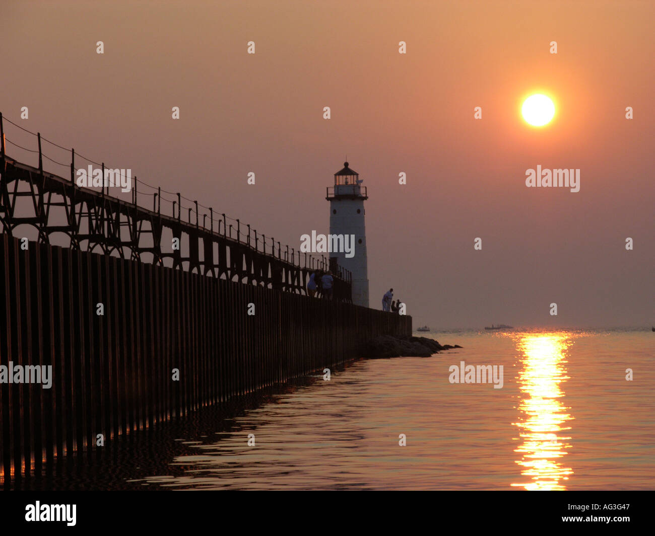 Sunset behind the lighthouse on Lake Michigan at Manistee Michigan beach Stock Photo