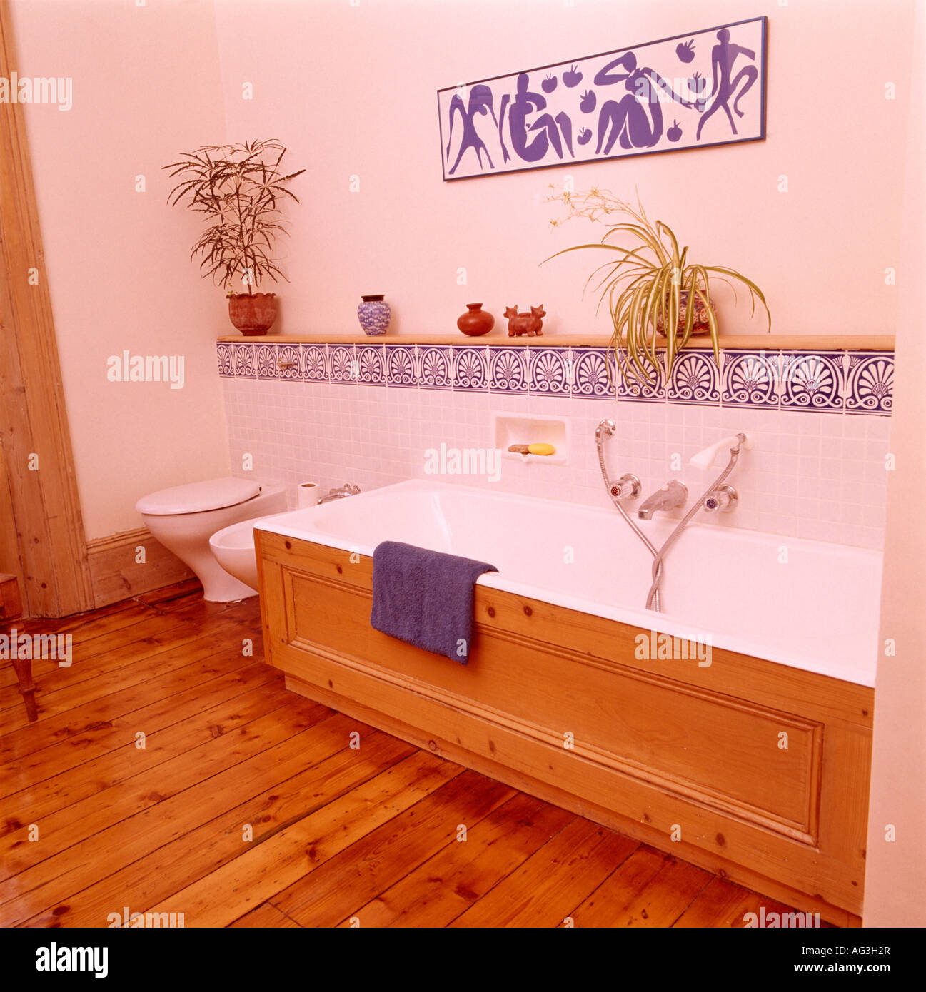Wooden panelling on bathtub in bathroom with blue and white tiling and