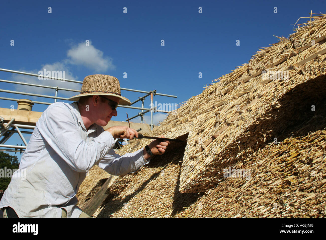 Thatcher at work on traditional English cottage roof. Landscape. Stock Photo