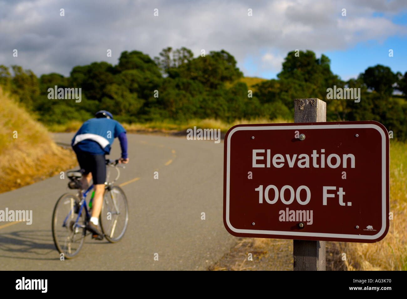 Bicycle rider going uphill on road past elevation marker sign Mount Diablo State Park California Stock Photo