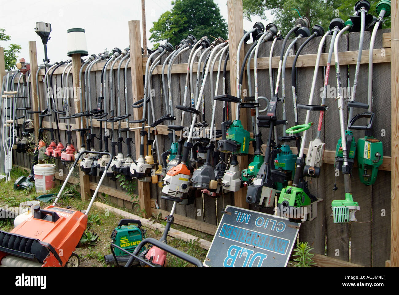 Display of gas and electric grass and weed trimmers hang on a fence at a flea market Stock Photo