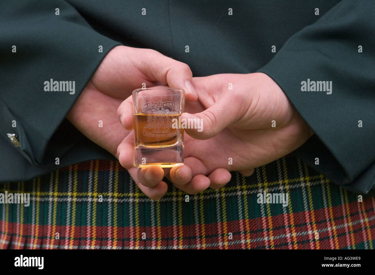 Highlander at Scottish Highland Games - Scotch whisky liqueur whiskey glass held behind the back of tartan plaid kilt, Scotland uk Stock Photo