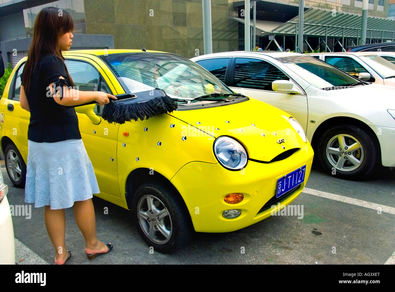 Beijing CHINA, Chinese Woman Dusting off her Chery Chinese Car in Parking lot of Business Center Stock Photo