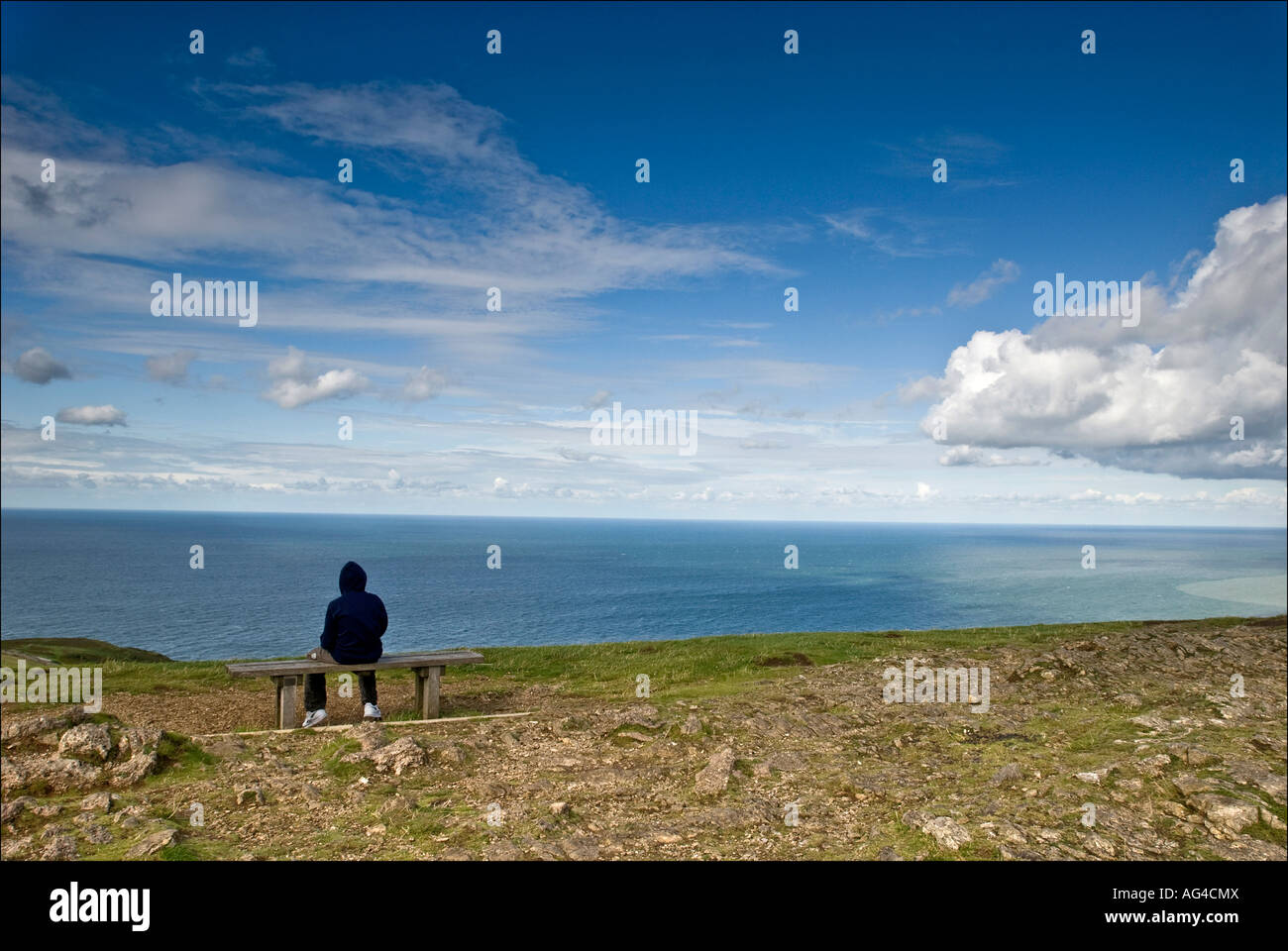 A solitary figure gazes across the sweep of the Irish Sea from the summit of the Great Orme in Llandudno Clwyd North Wales. Stock Photo