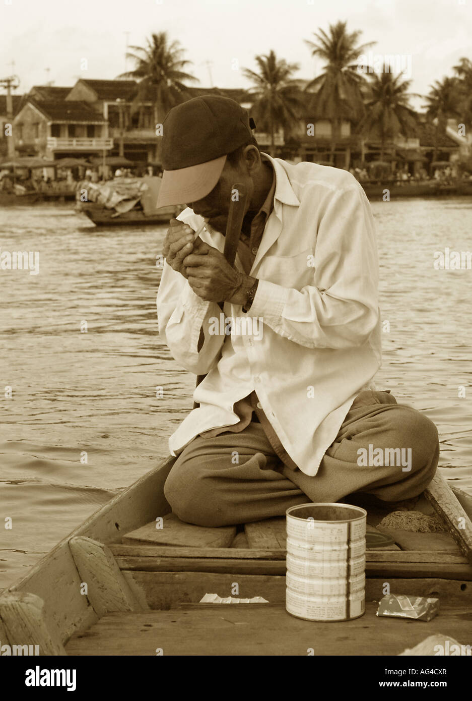 Taxi boat driver in Hoian Vietnam lights a cigarette Stock Photo - Alamy