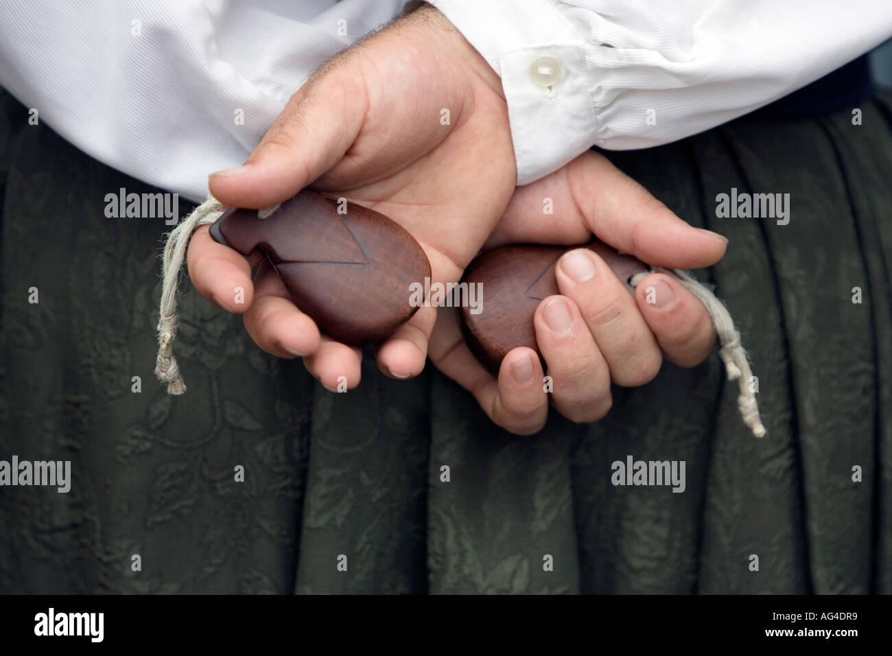 Spanish man holding two wooden in hands behind back, Plaza
