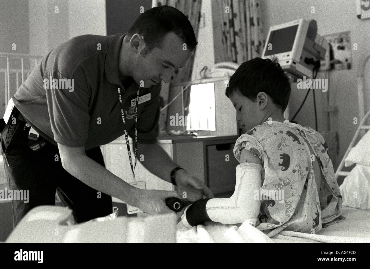 A male nurse tends to a young boy's broken arm in a children's ward of a hospital in north London, UK. Stock Photo