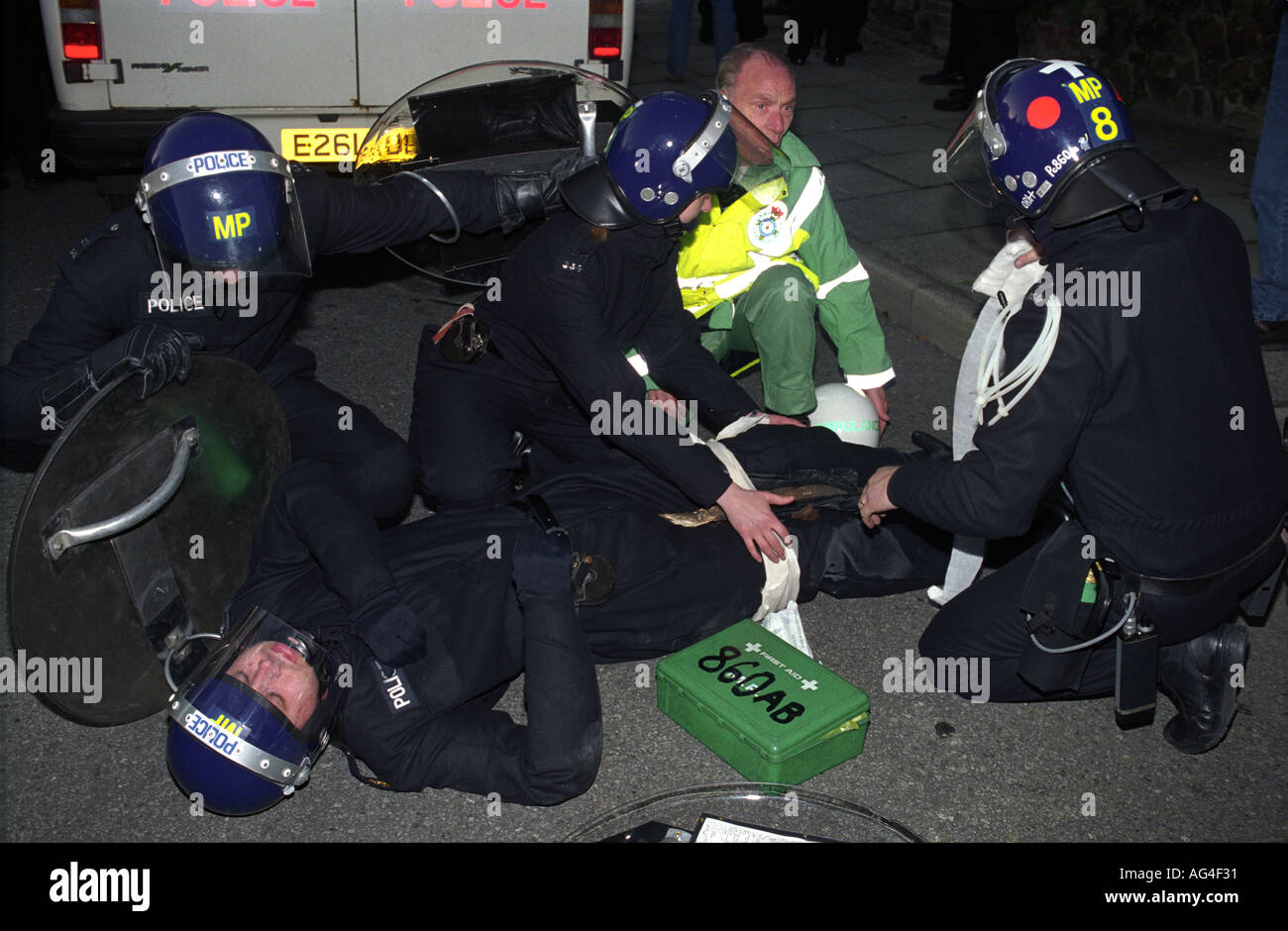 Fellow police officers and a medic tend to  policeman injured in riots at anti-British National Party march,Welling, London 1994 Stock Photo