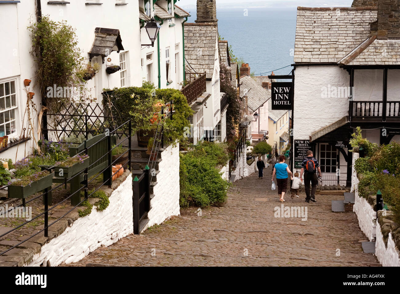 UK Devon Clovelly village visitors walking down the steep main street