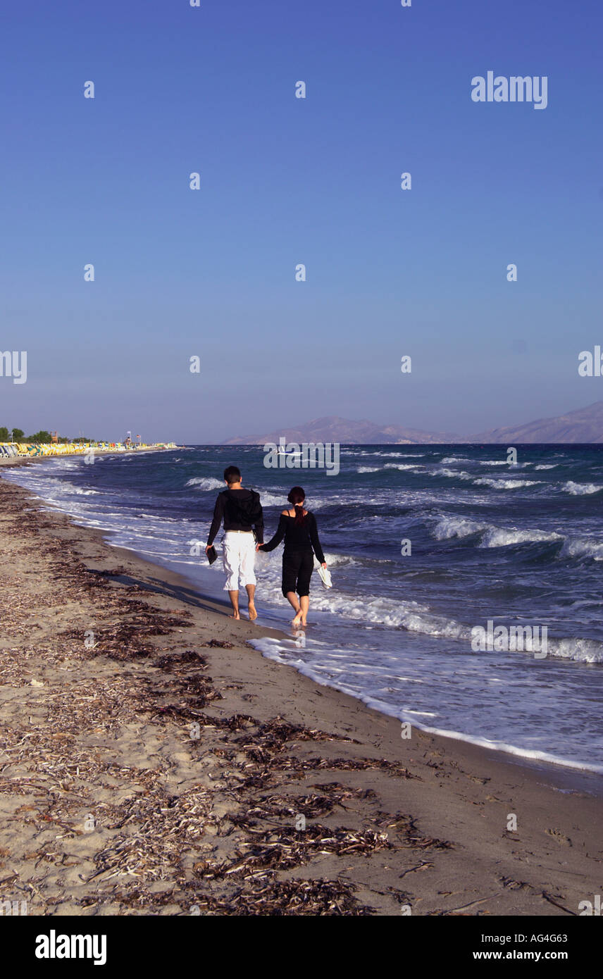 Young couple taking an early morning romantic strole along Tigaki beach on the Greek Island of Kos Stock Photo