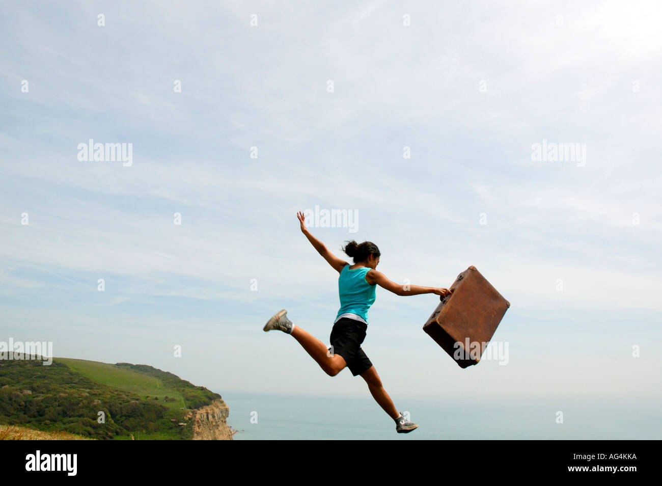 Young girl jumping with suitcase on cliffs Sarah Klein Stock Photo Alamy