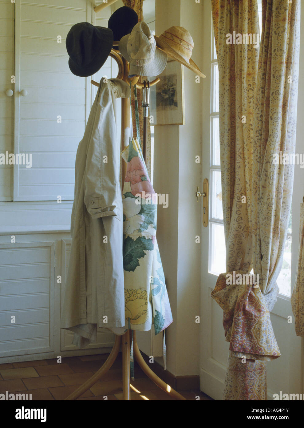 Coats and hats on bentwood hatstand in hall with neutral curtain Stock Photo