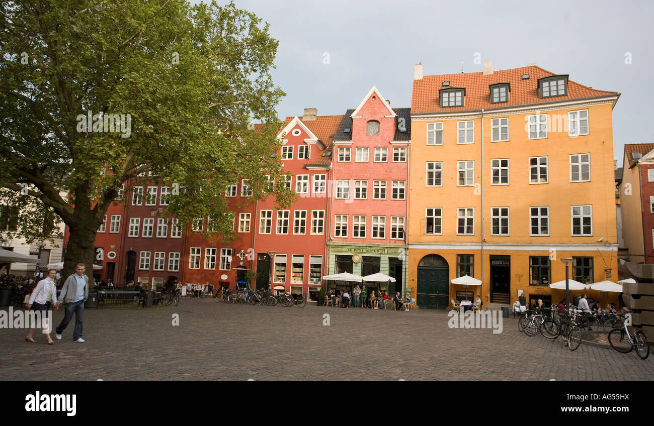 Copenhagen Square A couple crosses a cobbled square of brightly coloured buildings housing cafes and apartments Stock Photo