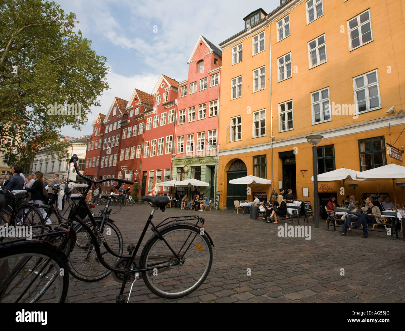 Calm Copenhagen Oasis A black bicycle parked under a tree in a square of brightly coloured buildings housing cafes and apartment Stock Photo