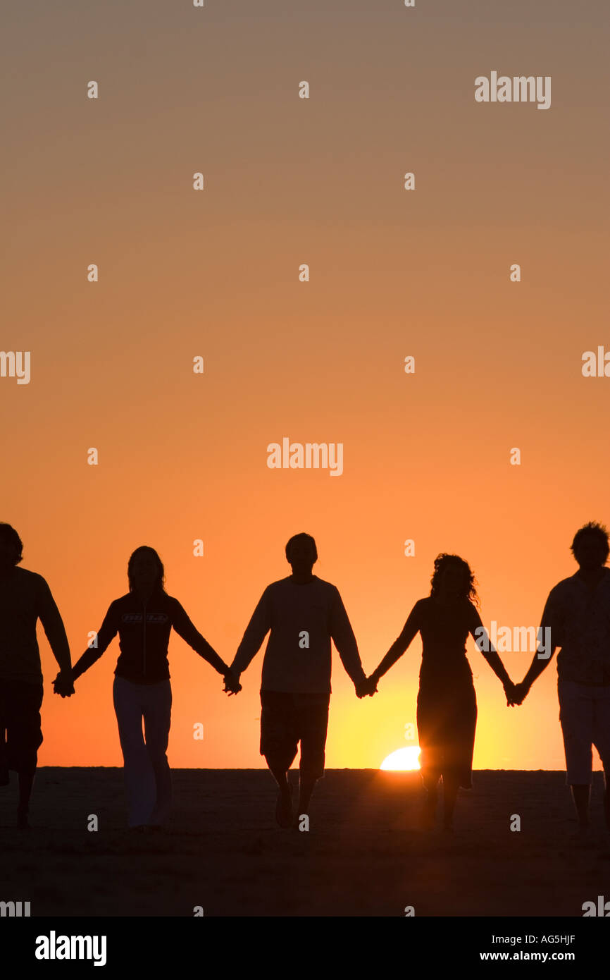 Group of best friends holding hands walking into the sunset Stock Photo