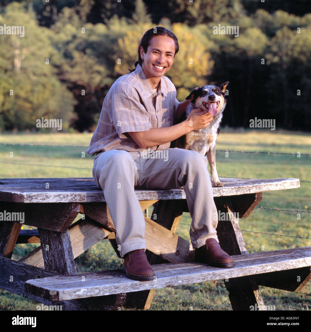 Man Sitting On A Picnic Table And Smiling With His Dog Stock Photo - Alamy