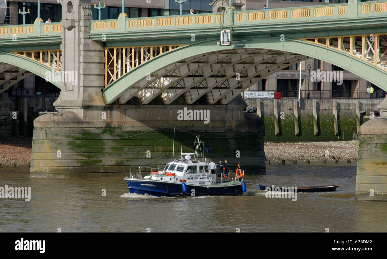 A skiff Penelope is towed up the River Thames under Southwark Bridge by the Port of London Harbour Master s launch Ravensbourne Stock Photo