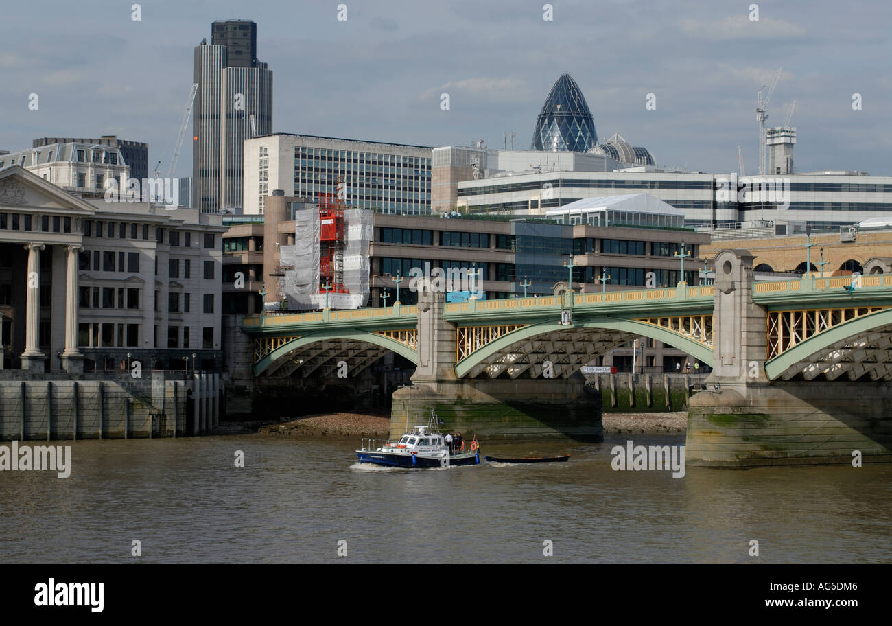A skiff Penelope is towed up the River Thames under Southwark Bridge by the Port of London Harbour Master s launch Ravensbourne Stock Photo