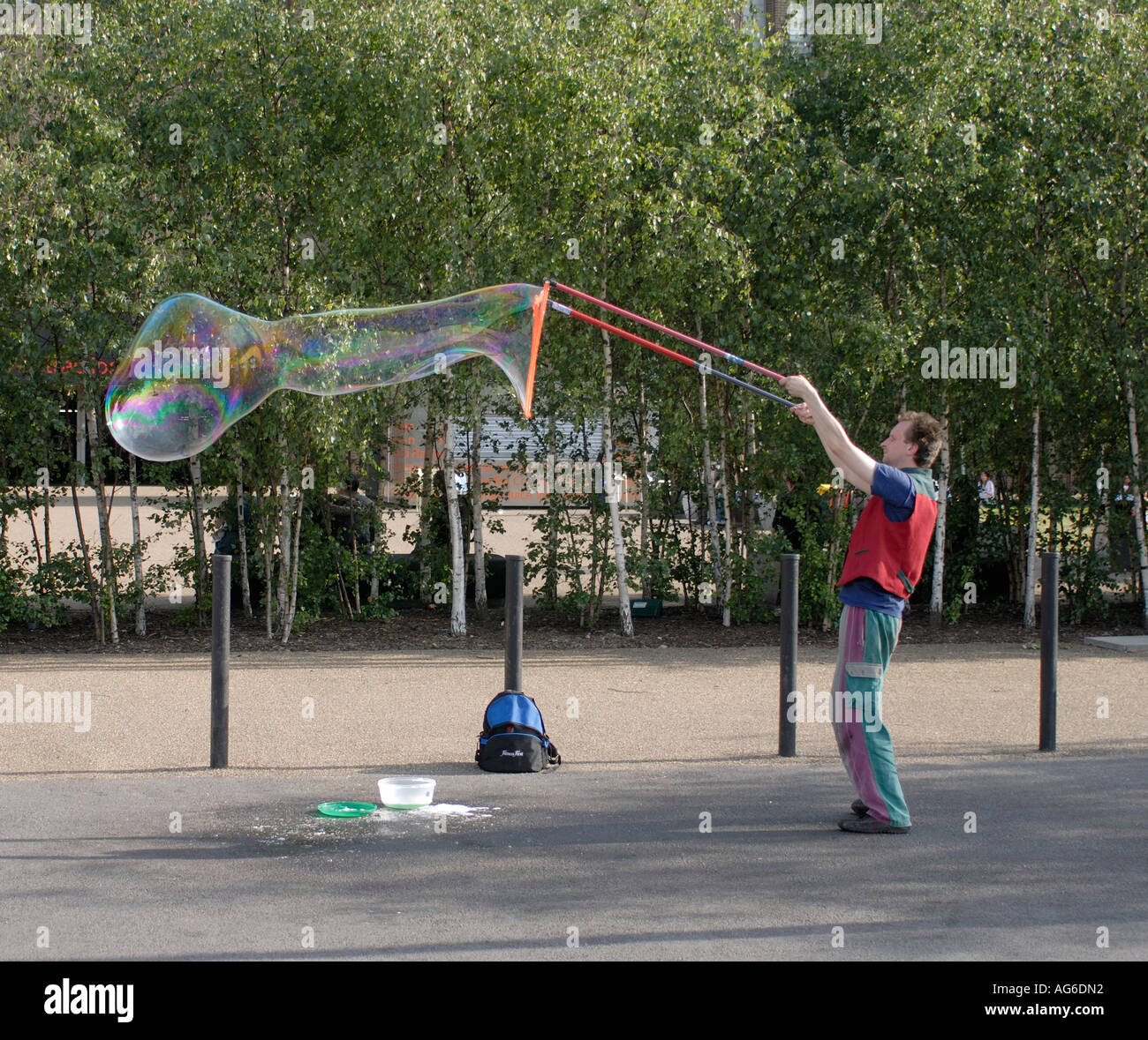 A street performer blows giant soap bubbles with rainbow colours outside the New Tate Gallery Southwark London UK 23 June 2006 Stock Photo