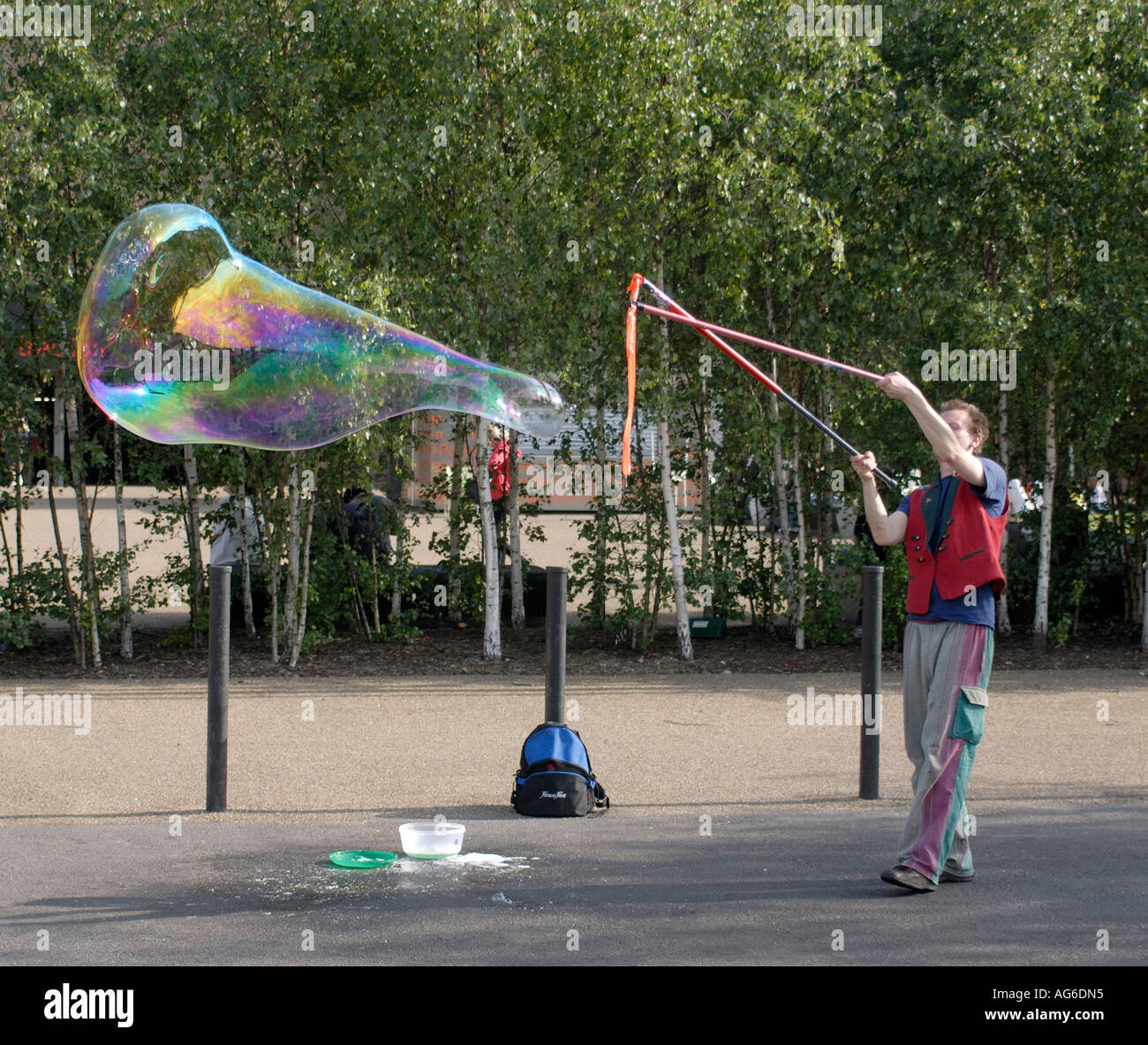 A street performer blows giant soap bubbles with rainbow colours outside the New Tate Gallery Southwark London UK 23 June 2006 Stock Photo