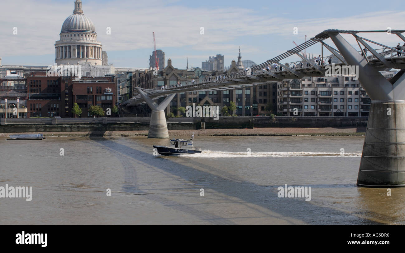 A river police boat speeds up the River Thames under the Millenium Bridge St Paul s Cathedral in the background City of London Stock Photo
