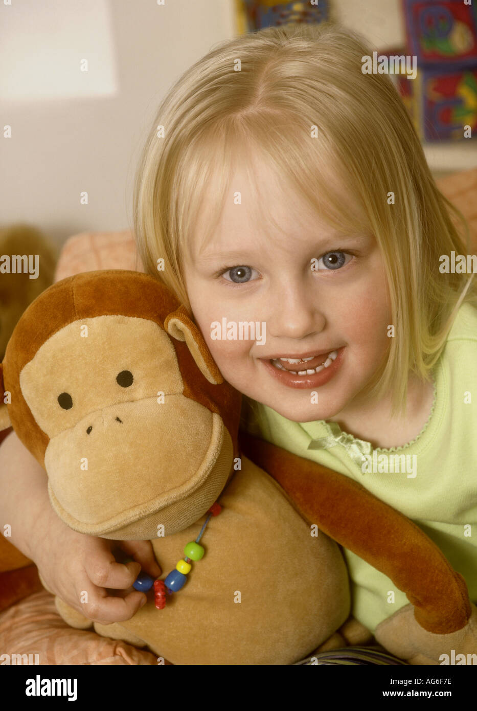 Young girl cuddling a soft toy laughing Stock Photo