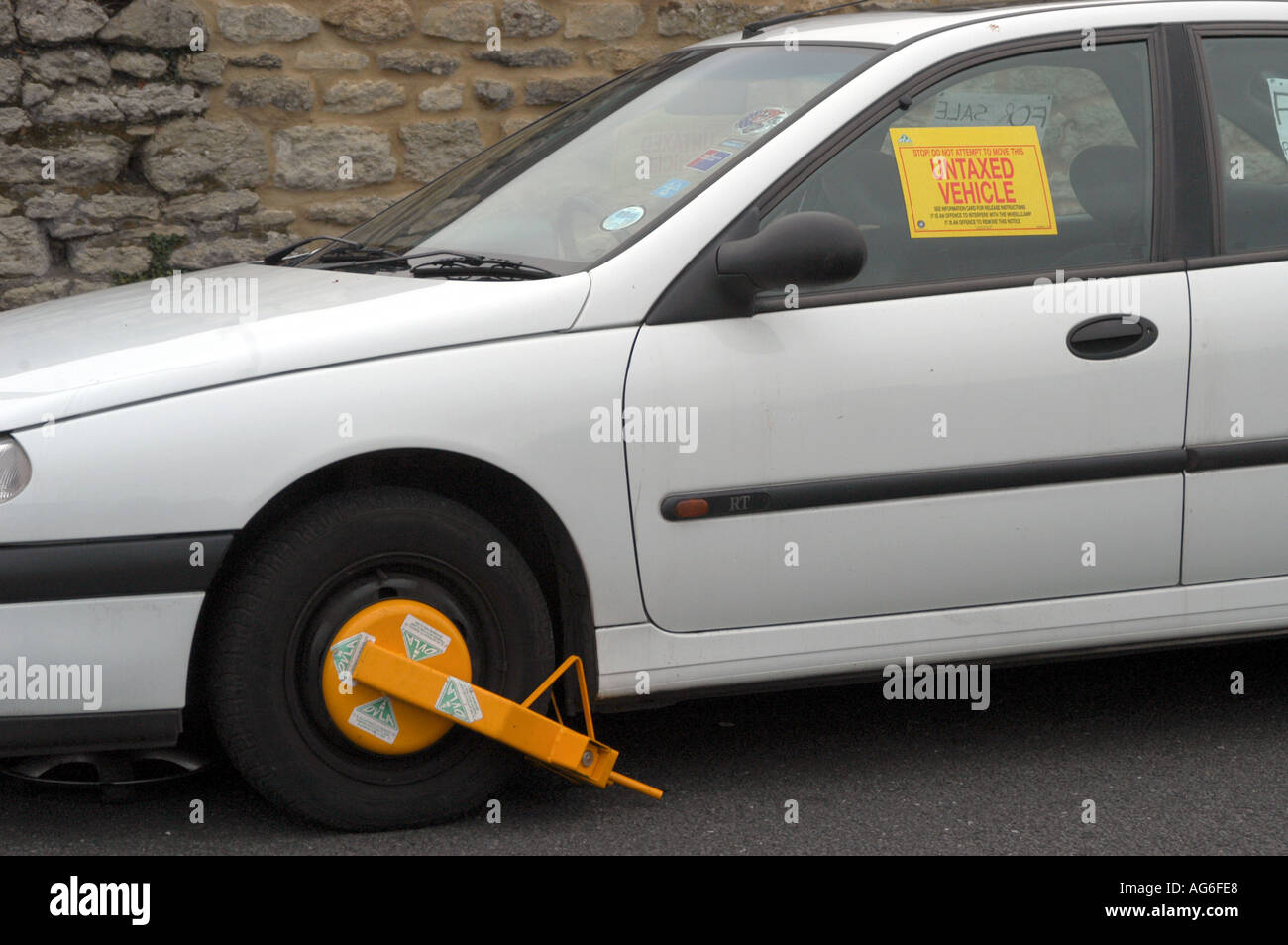 White car with DVLA wheel clamp and notice Stock Photo Alamy