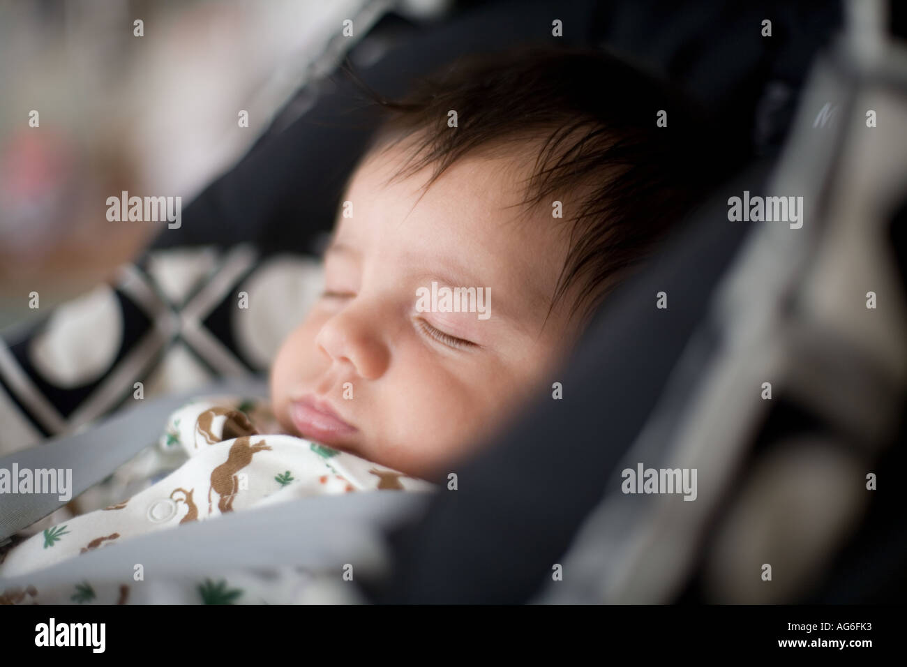 Baby boy sleeping strapped into a car seat Stock Photo