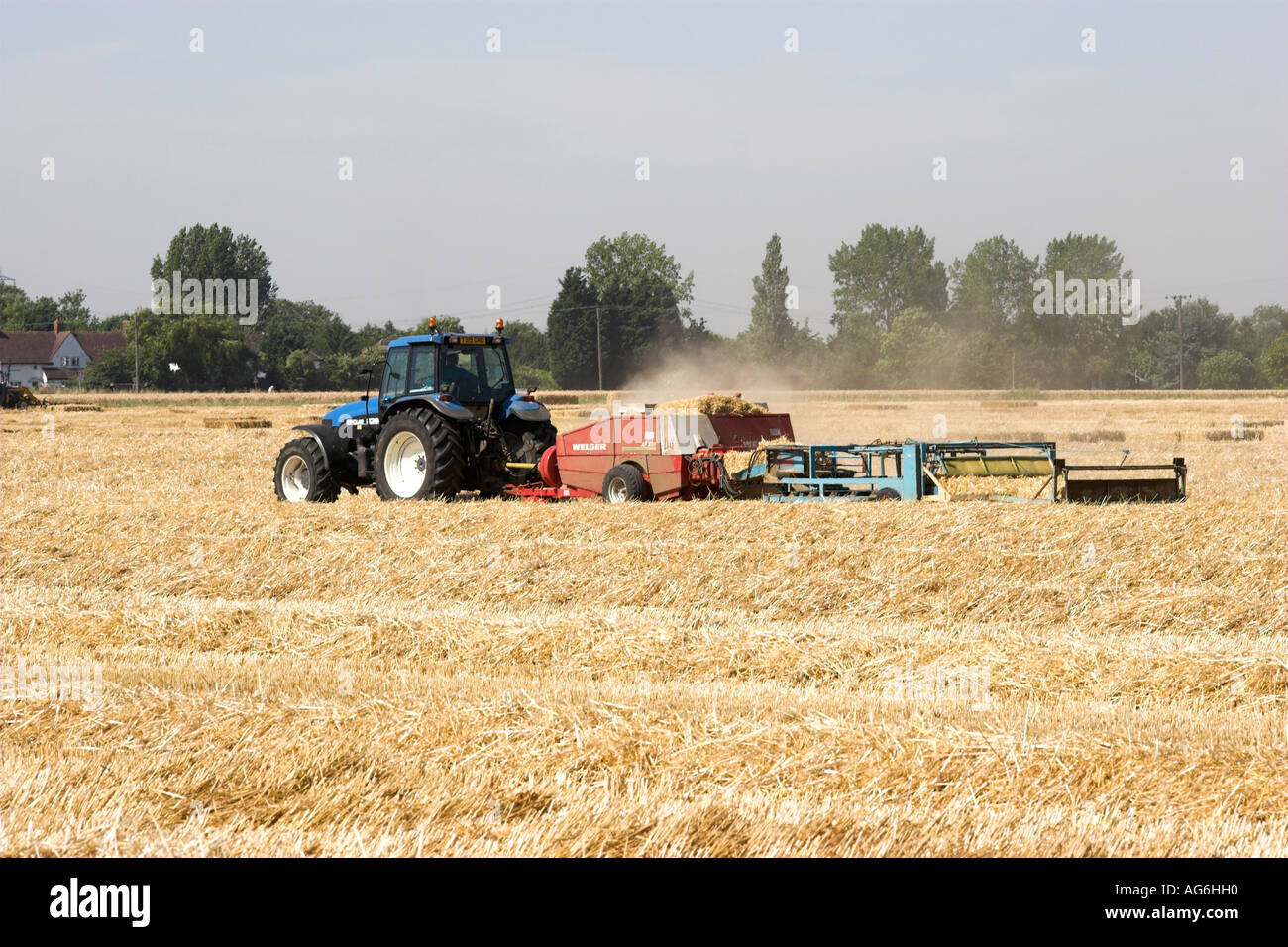 New Holland tractor and a Lely Welger baler AP830 baling straw in a field in Hertfordshire, England Stock Photo