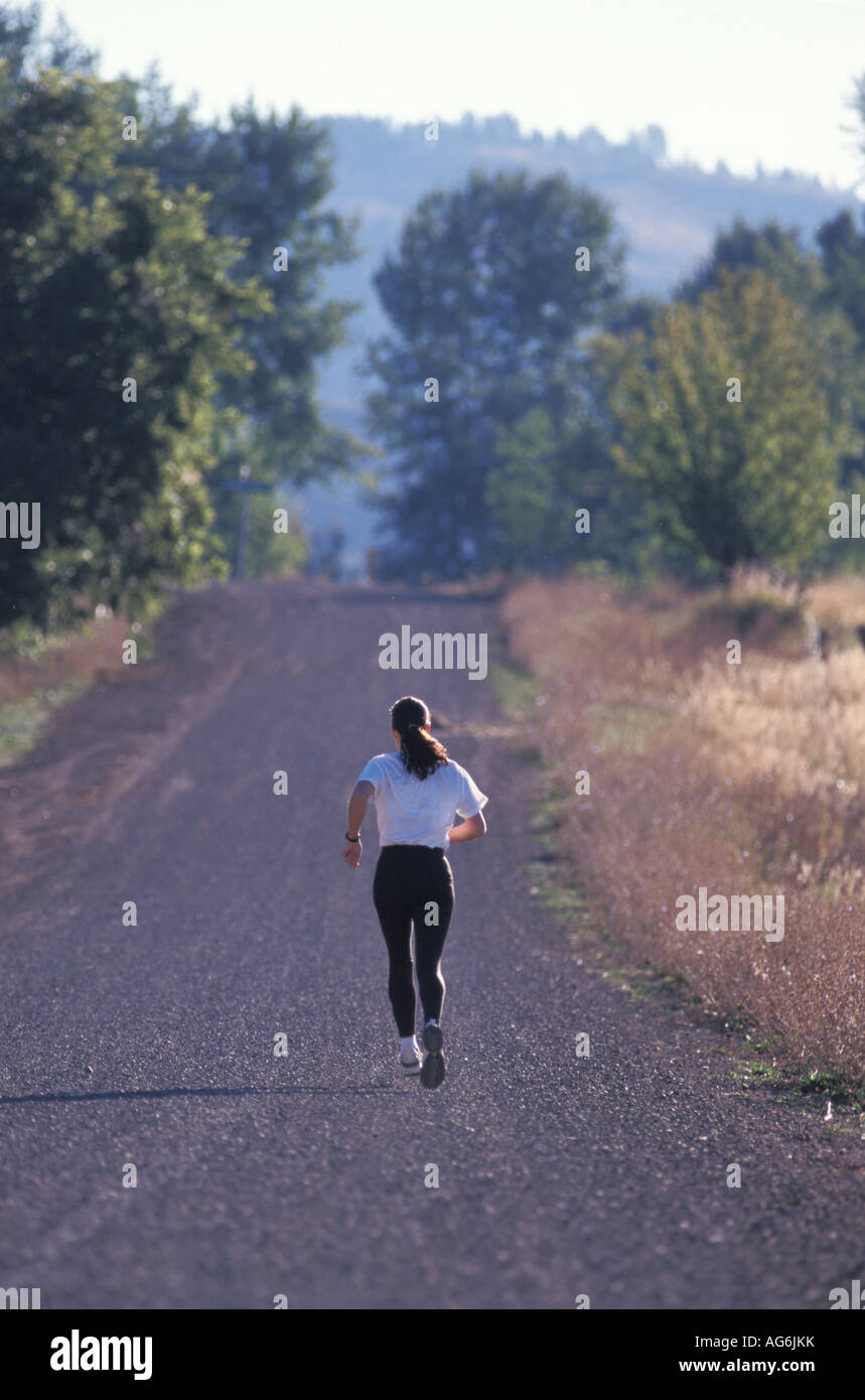 Caucasian Woman Jogging Away Down A Gravel Country Road Stock Photo Alamy