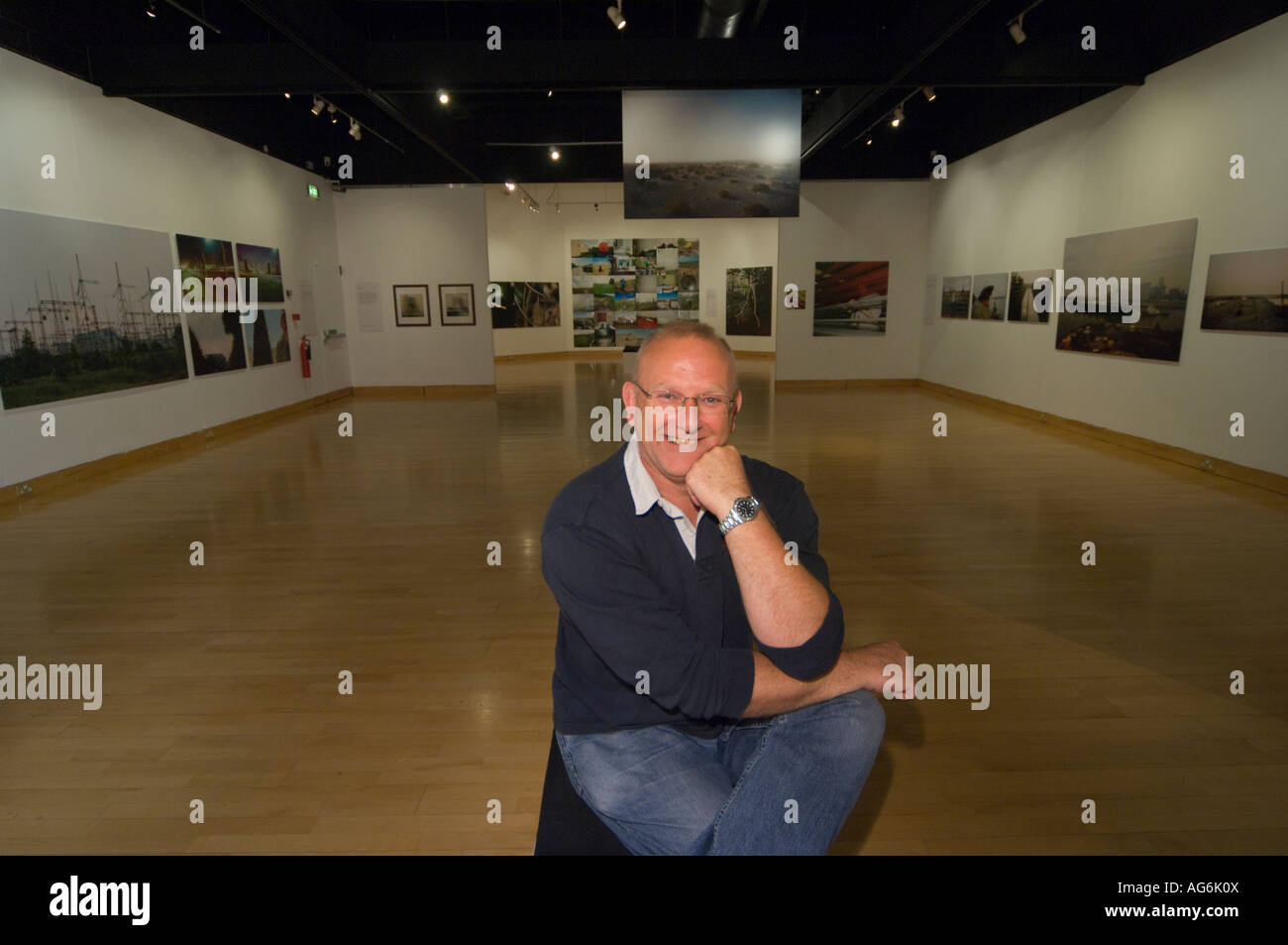 Photographer artist John Darwell sitting in the gallery during his solo exhibition at Tullie House, Carlisle Stock Photo