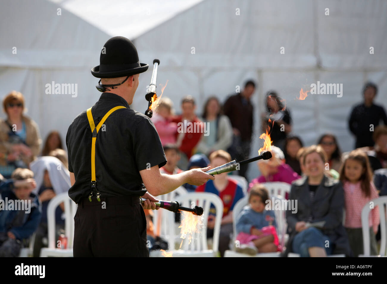 busking juggler juggling with flame sticks on fire in front of audience