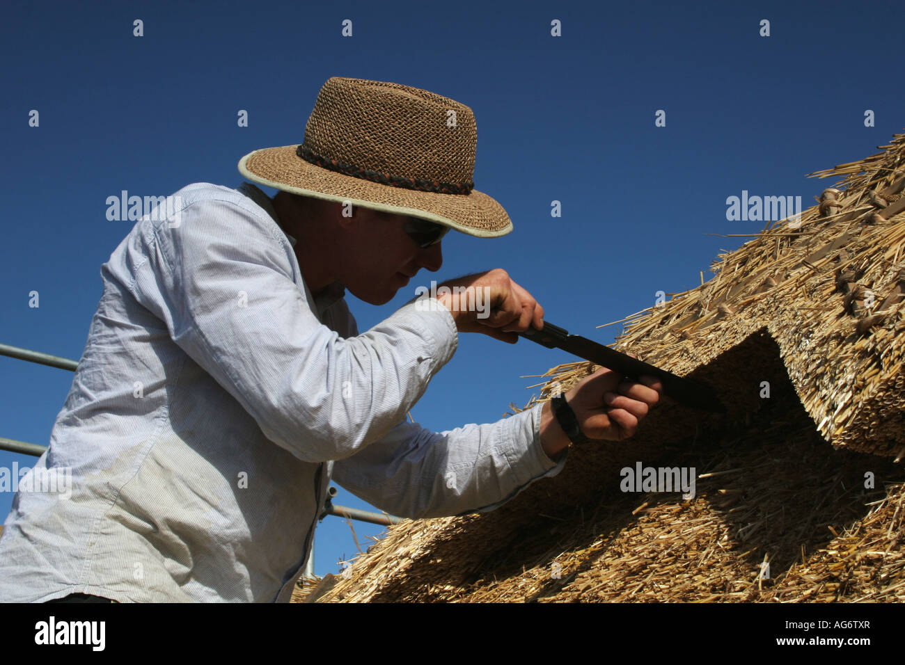 Thatcher at work on traditional English cottage roof. Close up landscape. Stock Photo