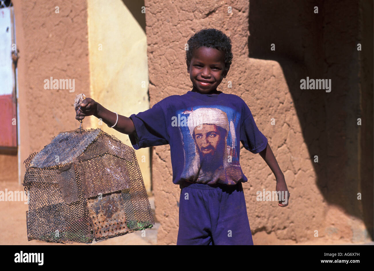 Niger Agadez Boy holding lizard's cage and wearing T-shirt with image of Osama Bin Laden Stock Photo
