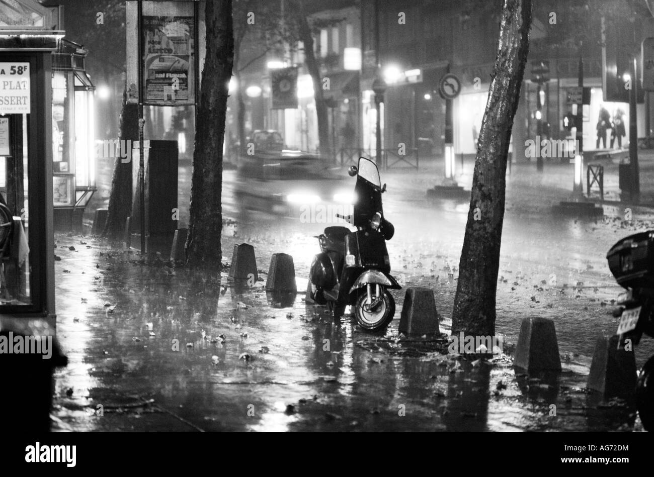 A scooter parked on a pavement on Boulevard Saint Michel in Paris during a rainstorm at night Stock Photo