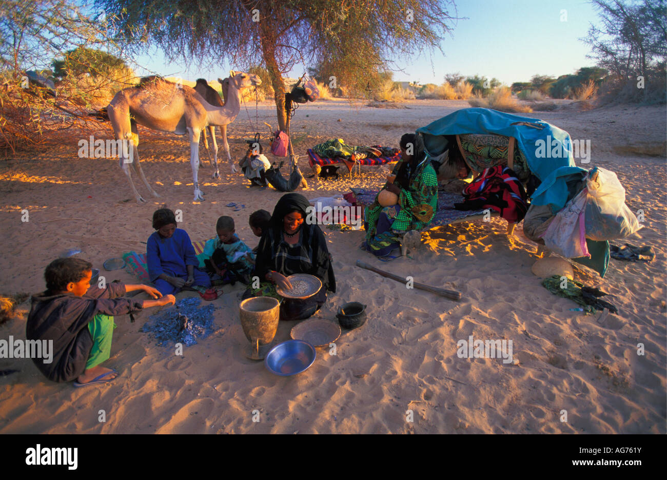 Niger Ifrouane Woman of Tuareg tirbe preparing food while children sitting Stock Photo