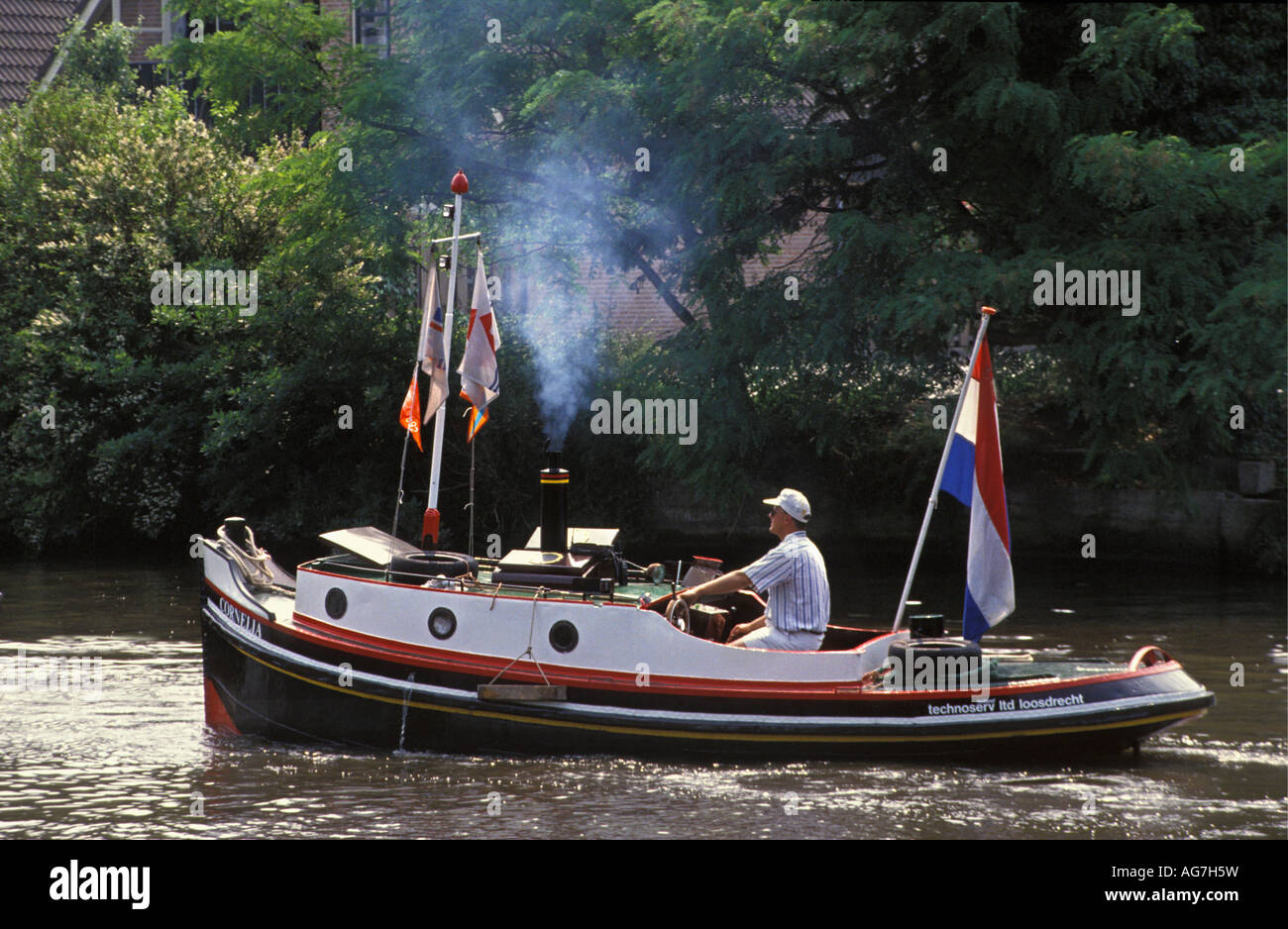 Netherlands Nieuwersluis Man traveling in small old fashioned steam boat Stock Photo
