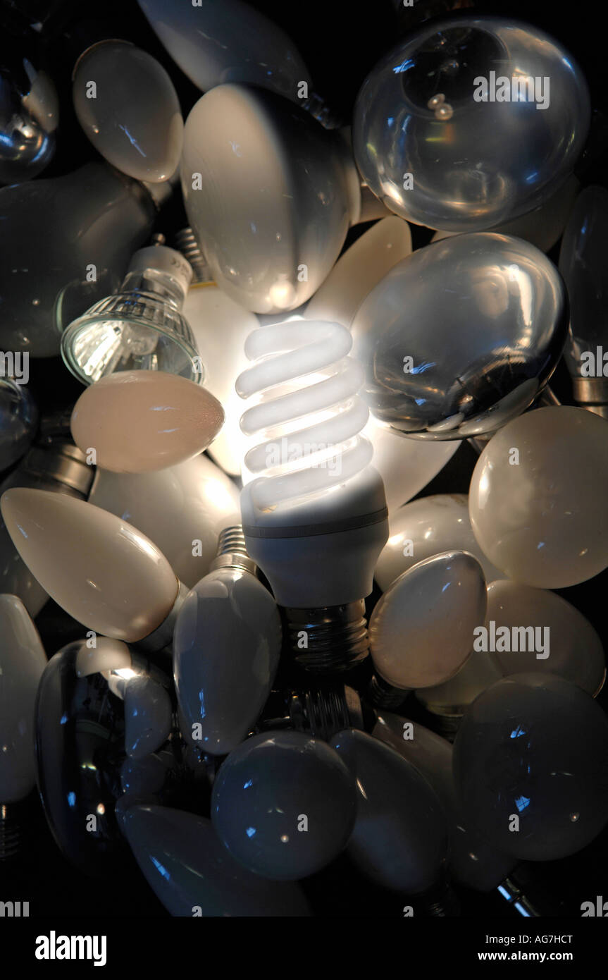 High energy efficient lamp glowing in the middle of a background group of mixed used lamps and bulbs Stock Photo