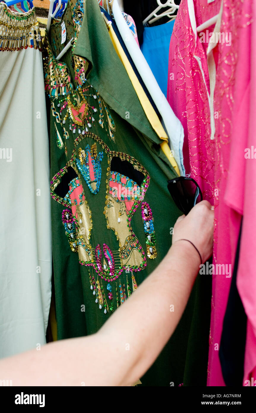 Womans arm browsing through garments for sale in street market Stock