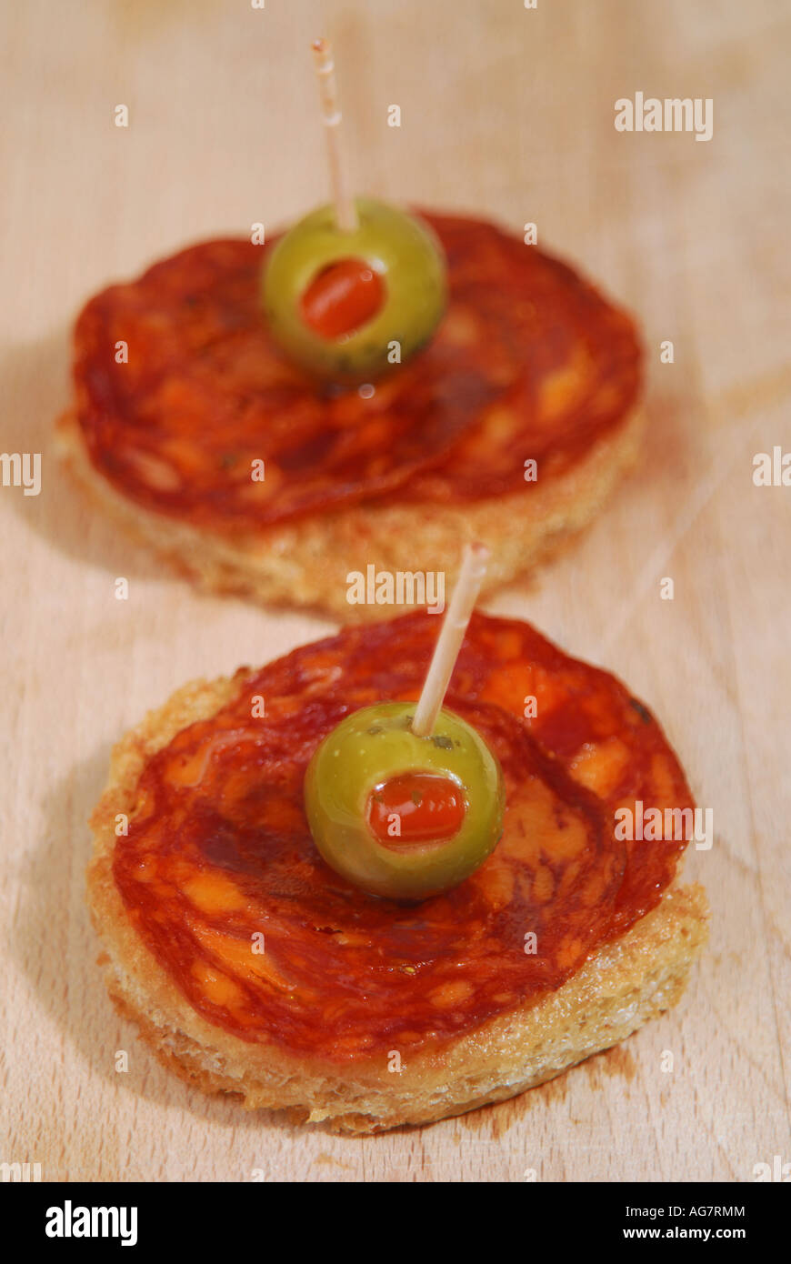 Slices of chorizo Iberico de Bellota with pimento-stuffed olives on crispy olive-oil fried bread Stock Photo