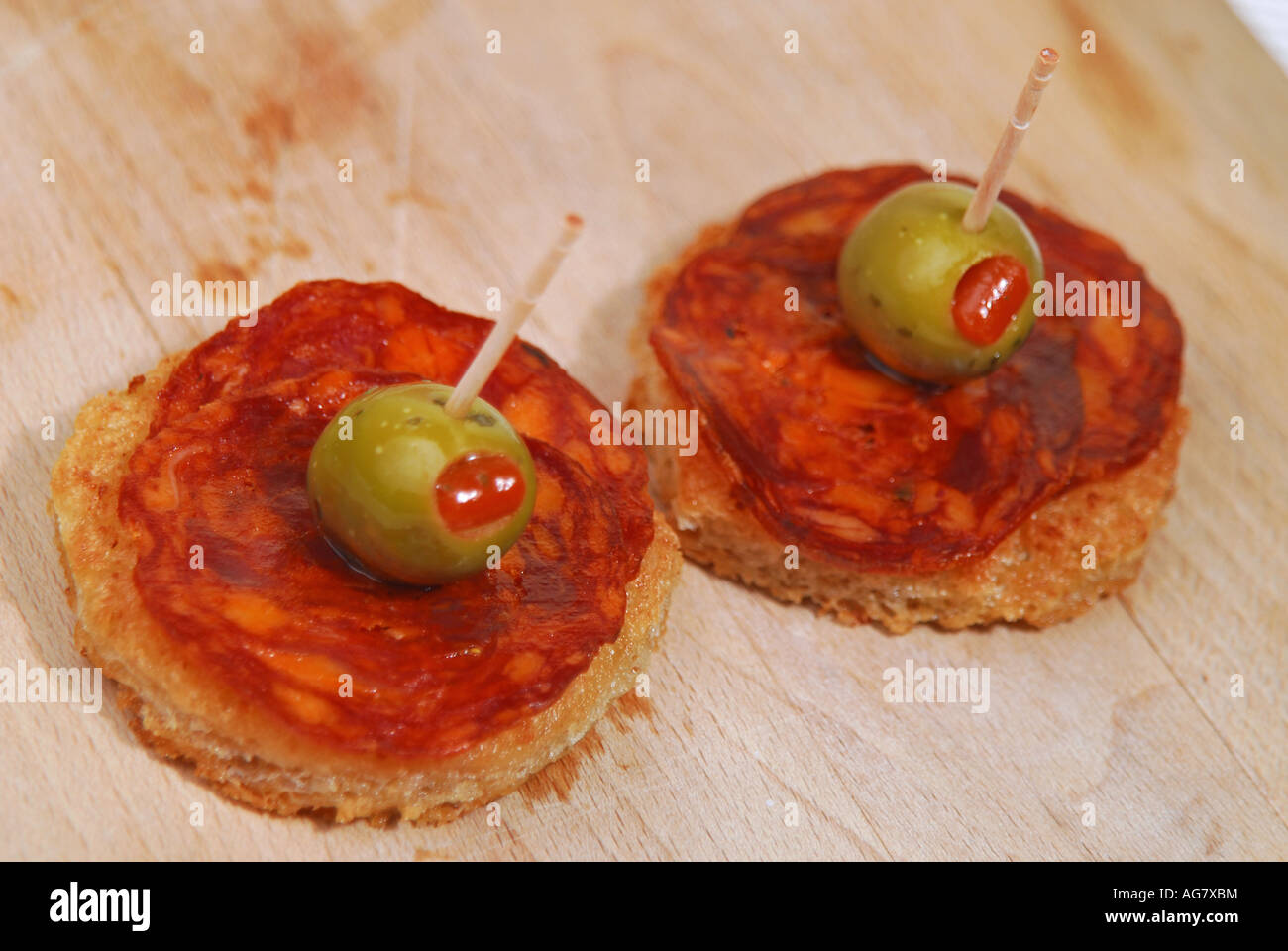 Slices of chorizo Iberico de Bellota with pimento-stuffed olives on crispy olive-oil fried bread Stock Photo