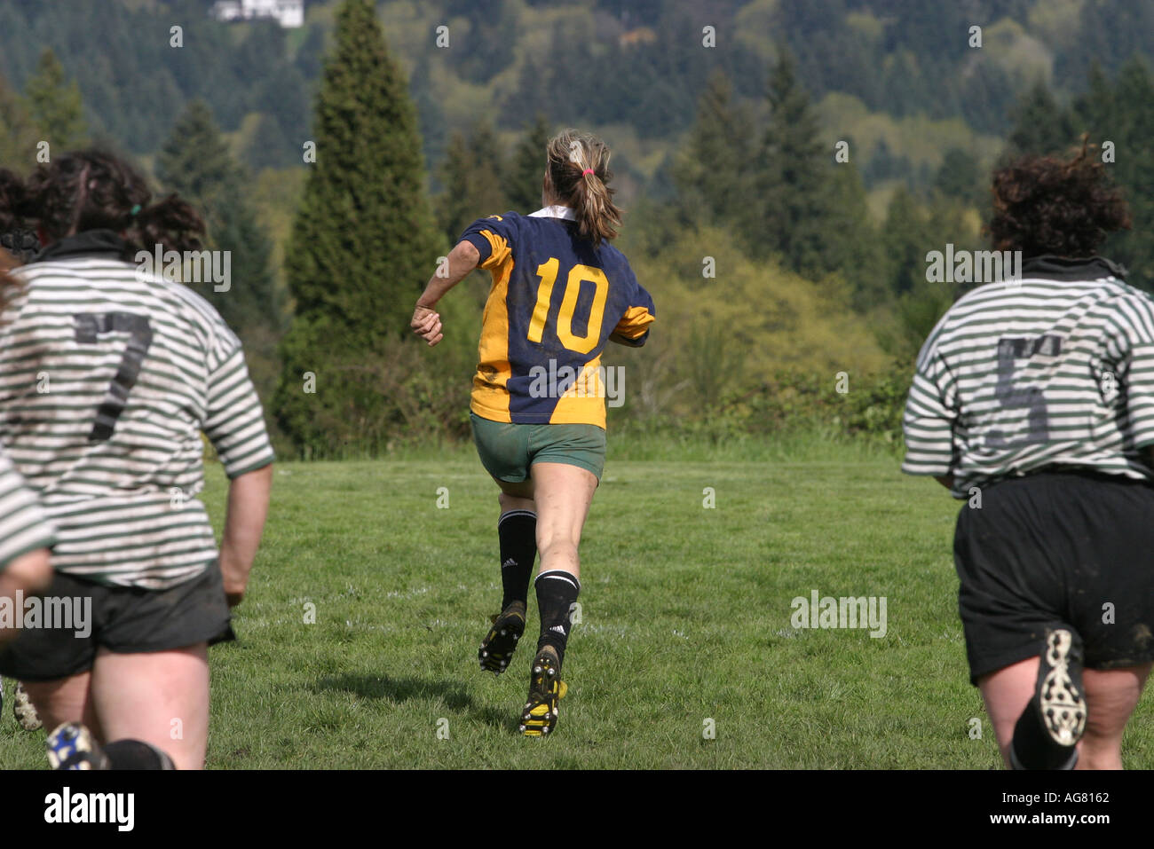 A women s rugby game in action as a woman runs with the ball at a game in Oregon Stock Photo