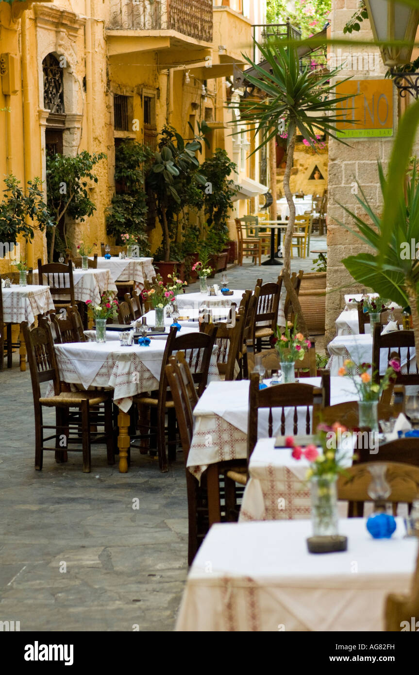 Narrow street lined with restaurant chairs and tables in Chania Crete. Stock Photo